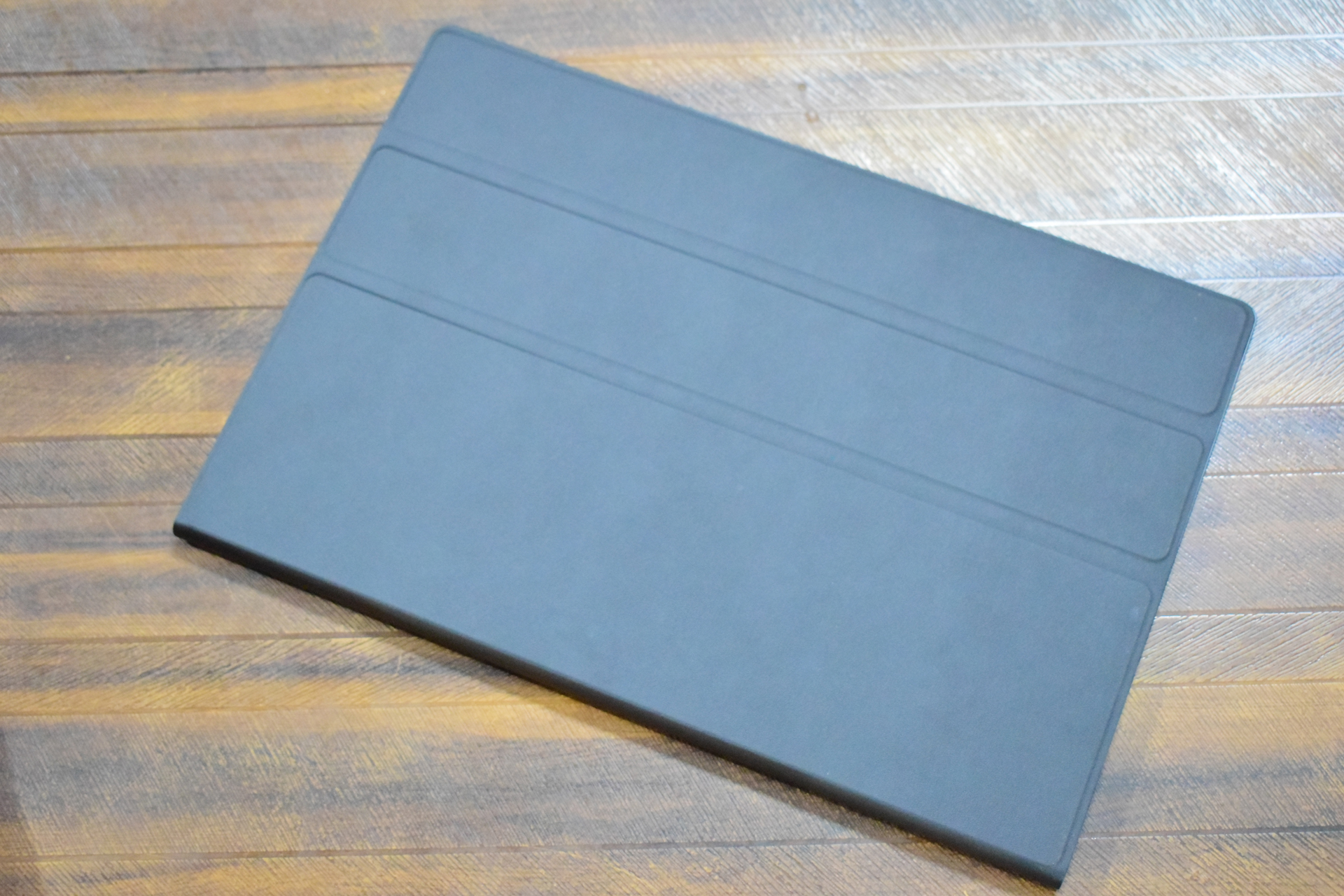 Μια κλειστή μαύρη θήκη tablet βρίσκεται σε μια ξύλινη επιφάνεια.