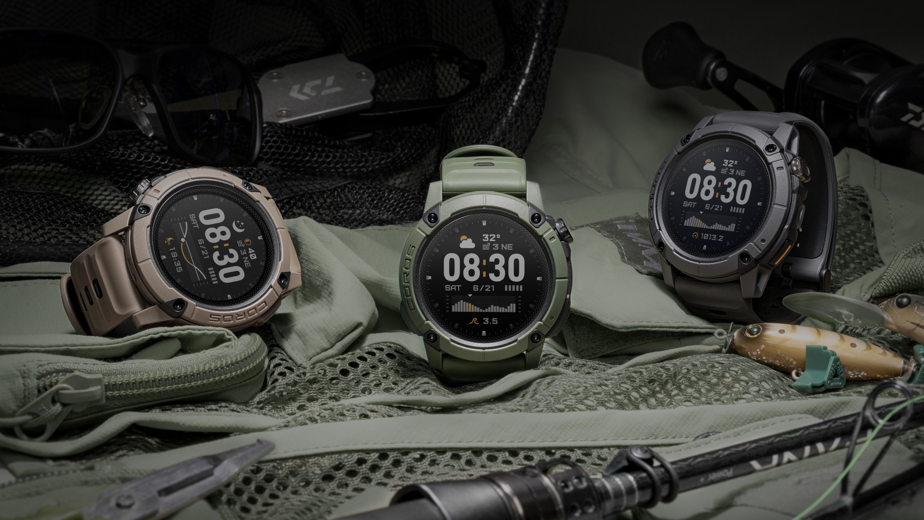 A photo of the green, grey, and brown COROS NOMAD watches sitting on a tent with camping equipment nearby.