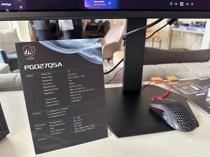 An ASRock PG027QSA monitor specifications card is displayed next to a gaming mouse on a desk.