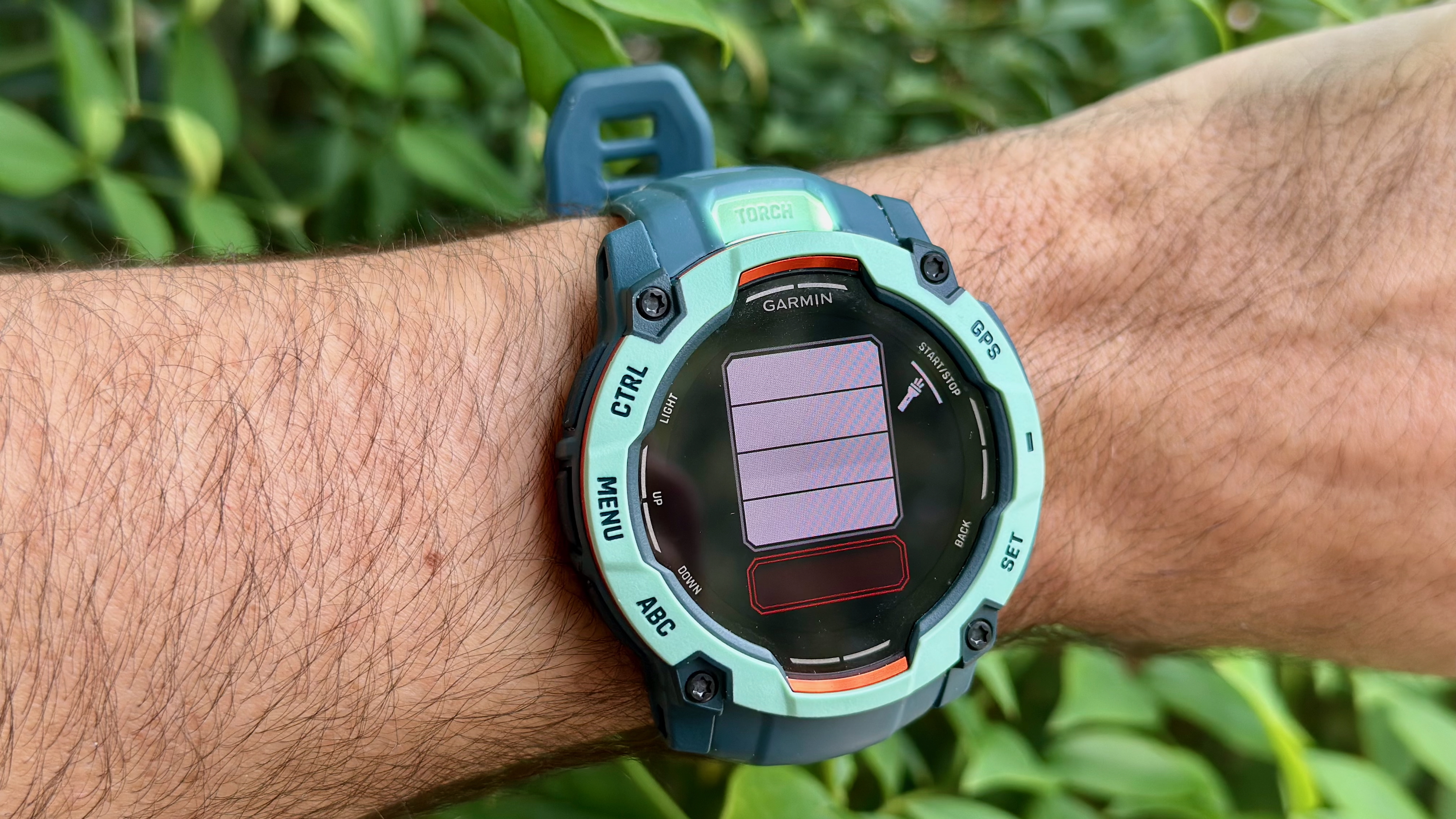 The Garmin Instinct 3 50mm AMOLED showing the "torch" or flashlight menu, with five different intensity levels (four white, one red) and a on-off toggle, with the full-intensity flashlight shining out of the top-back of the watch.