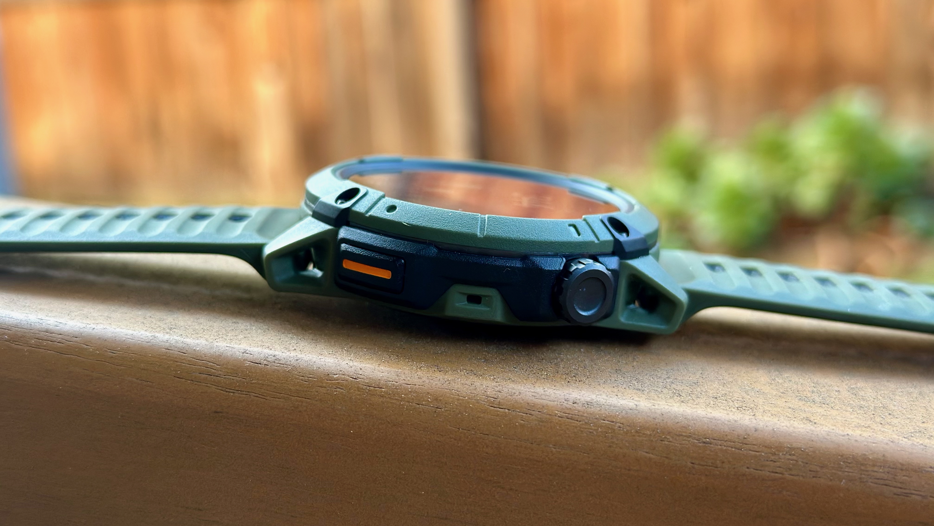 A side view of the COROS NOMAD laying on a chair arm, showing the crown and select/ back buttons.