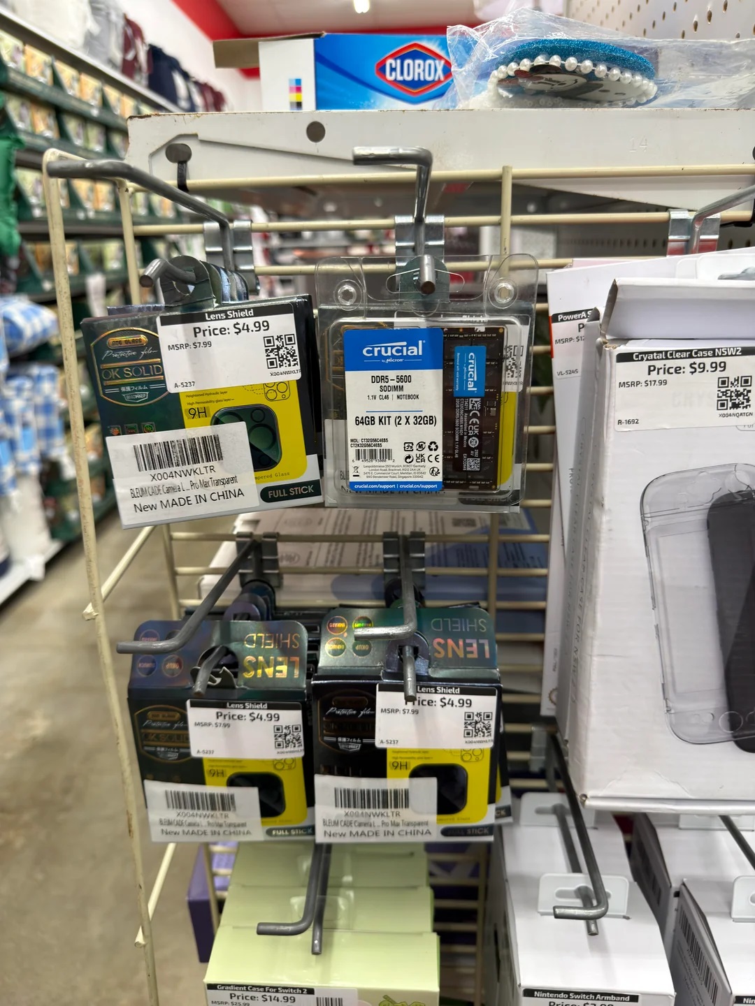 Ένα ράφι με οθόνη λιανικής που διαθέτει κιτ RAM 64 GB (2 x 32 GB) Crucial DDR5-5600 με συσκευασία που δείχνει «5000M» και «1.5V CL40», με τιμή 9,99 $, μαζί με διάφορα τεχνολογικά αξεσουάρ και προϊόντα Clorox στο φόντο.