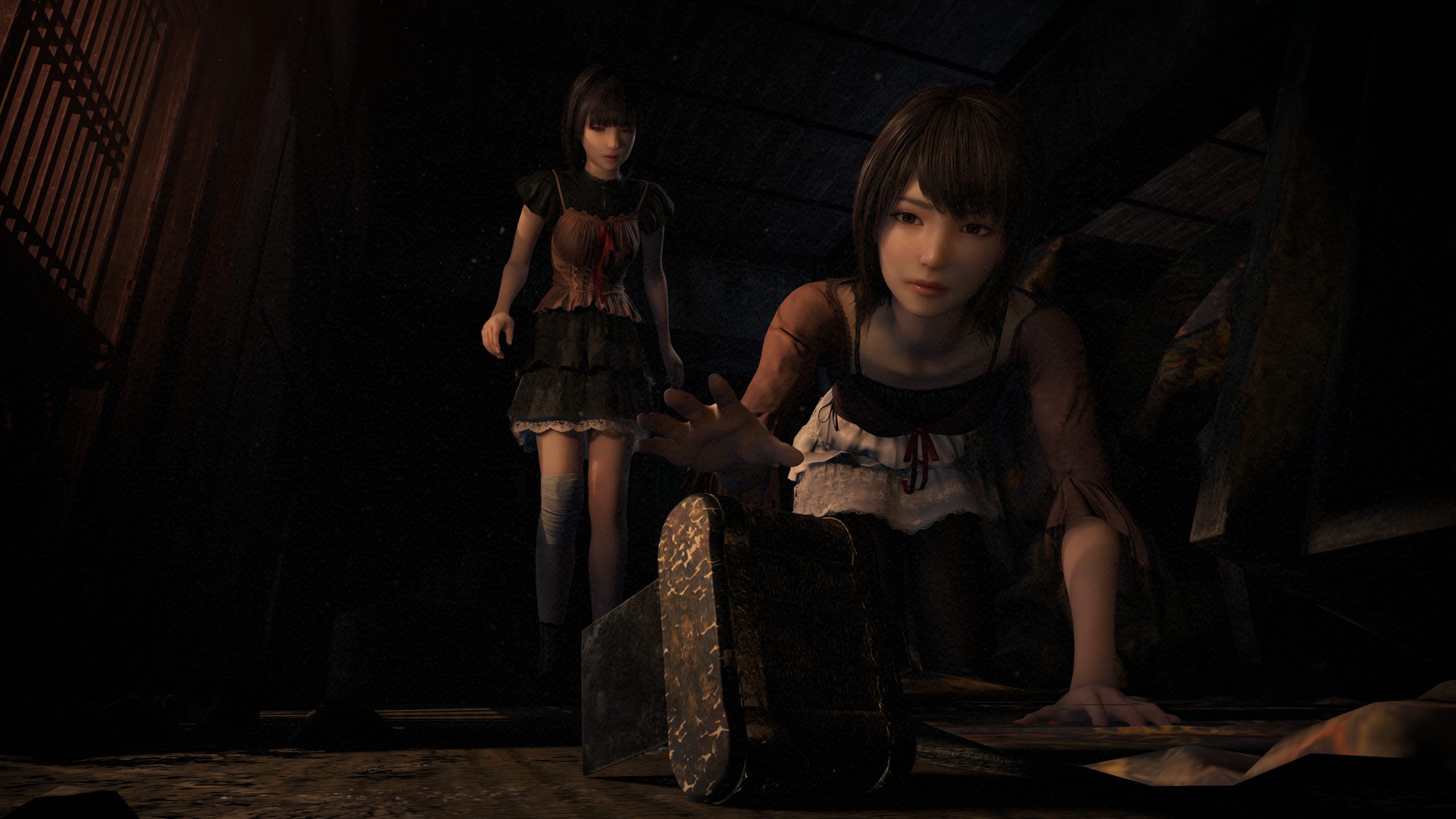 Two female characters in Fatal Frame 2 Crimson Butterfly Remake, with one reaching for a mysterious object in a dimly lit, attic-like