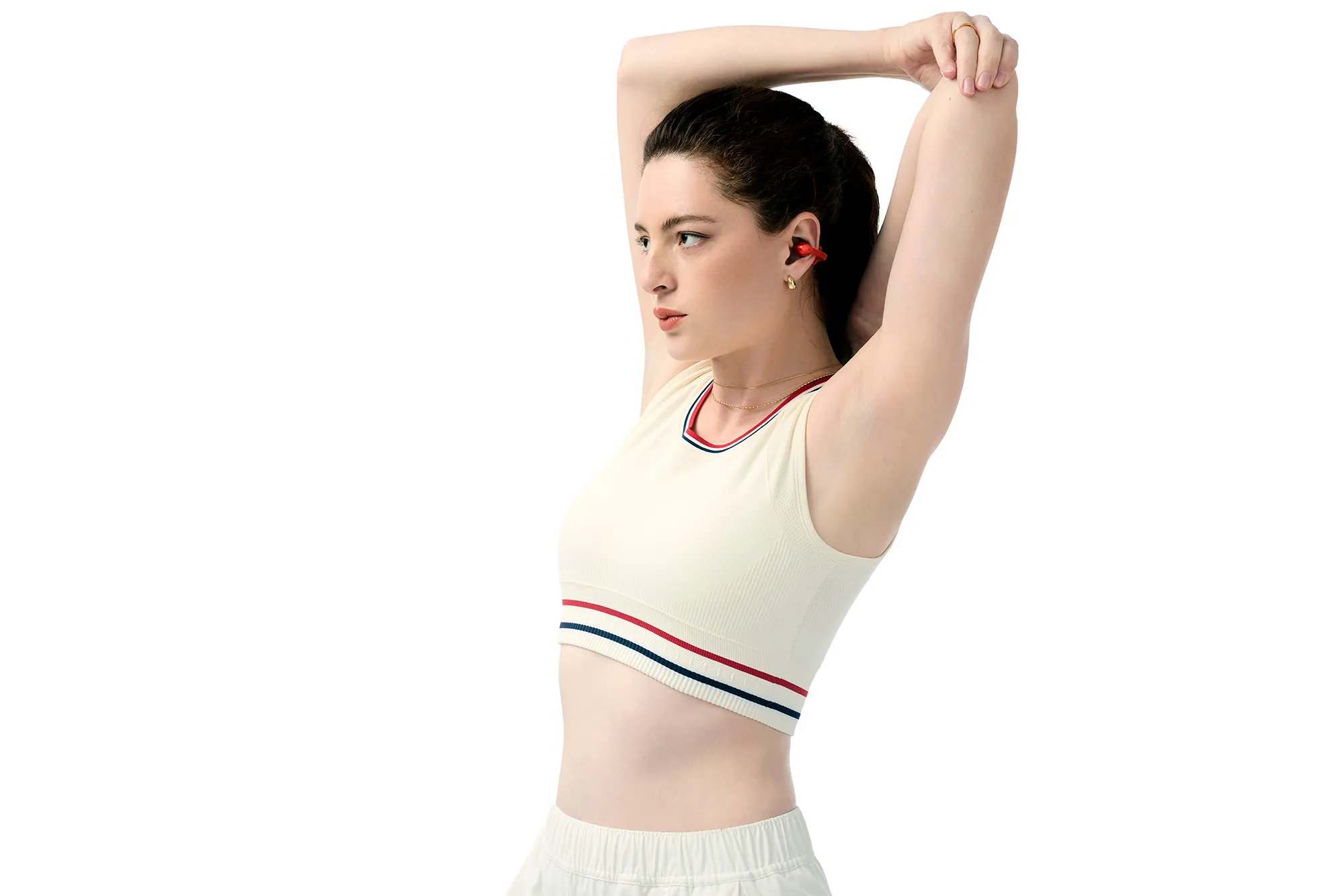 Μελαχρινή γυναίκα με ενδυμασία τένις που φοράει κόκκινο SHOKZ OpenDots ONE σε λευκό φόντο