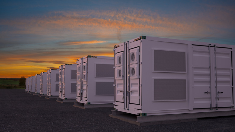 πολλά δοχεία αποθήκευσης στοιχείων μπαταρίας με τον ήλιο να δύει στο βάθος