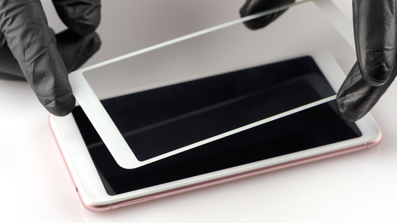 Ένα άτομο που εγκαθιστά ένα προστατευτικό οθόνης σε ένα smartphone