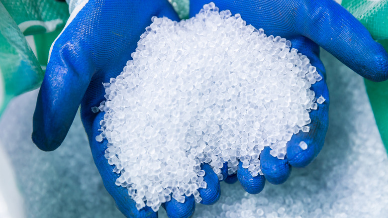 Ένα άτομο που φοράει γάντια κρατώντας σφαιρίδια από ανακυκλωμένο πλαστικό.