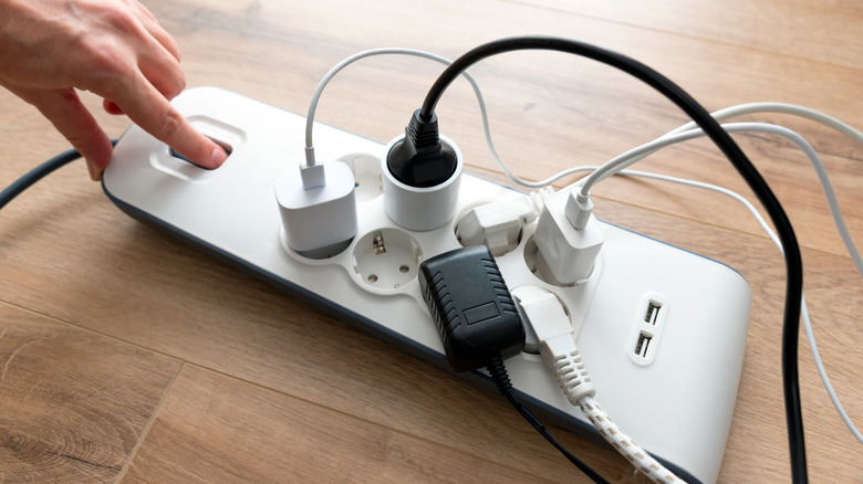 Ένα άτομο που πατά το κουμπί λειτουργίας ενός πολύπριζου