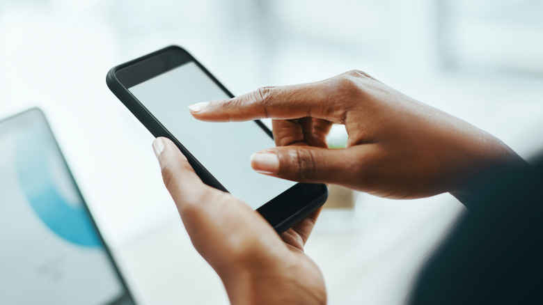 Ένα άτομο που αγγίζει την οθόνη του smartphone του με ένα δάχτυλο