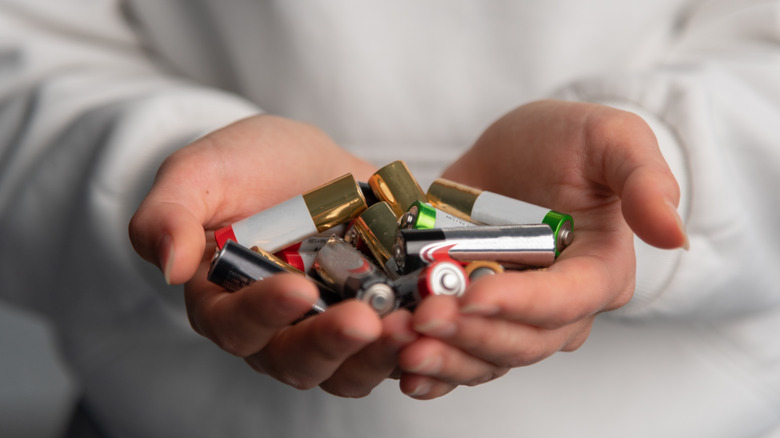 Ένα χέρι που κρατά ένα μάτσο μπαταρίες ΑΑ.