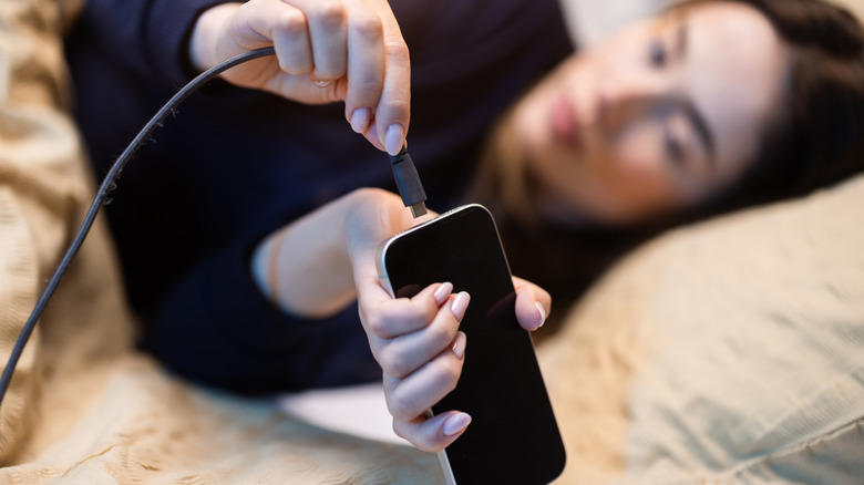 Χρήση τηλεφώνου στο κρεβάτι ενώ φορτίζει η μπαταρία.