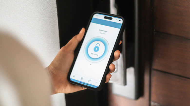 Ένα άτομο που χρησιμοποιεί μια εφαρμογή σε ένα iPhone για να ξεκλειδώσει μια έξυπνη κλειδαριά.