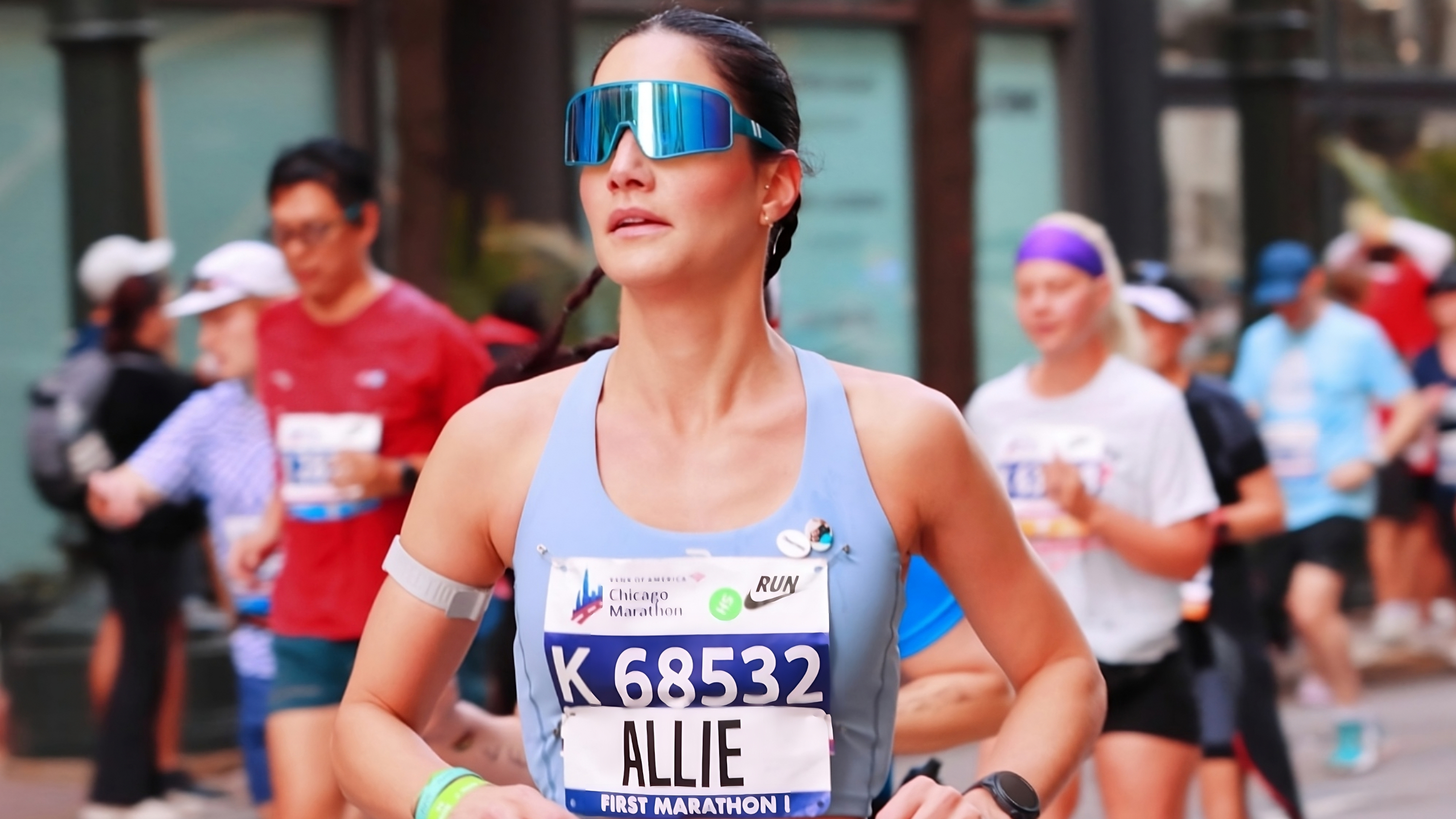 μια γυναίκα που τρέχει έναν μαραθώνιο φορώντας γυαλιά ηλίου